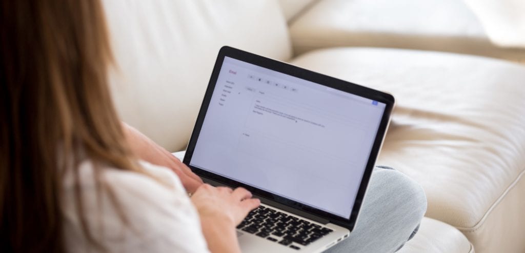 lady sitting on couch looking at a laptop